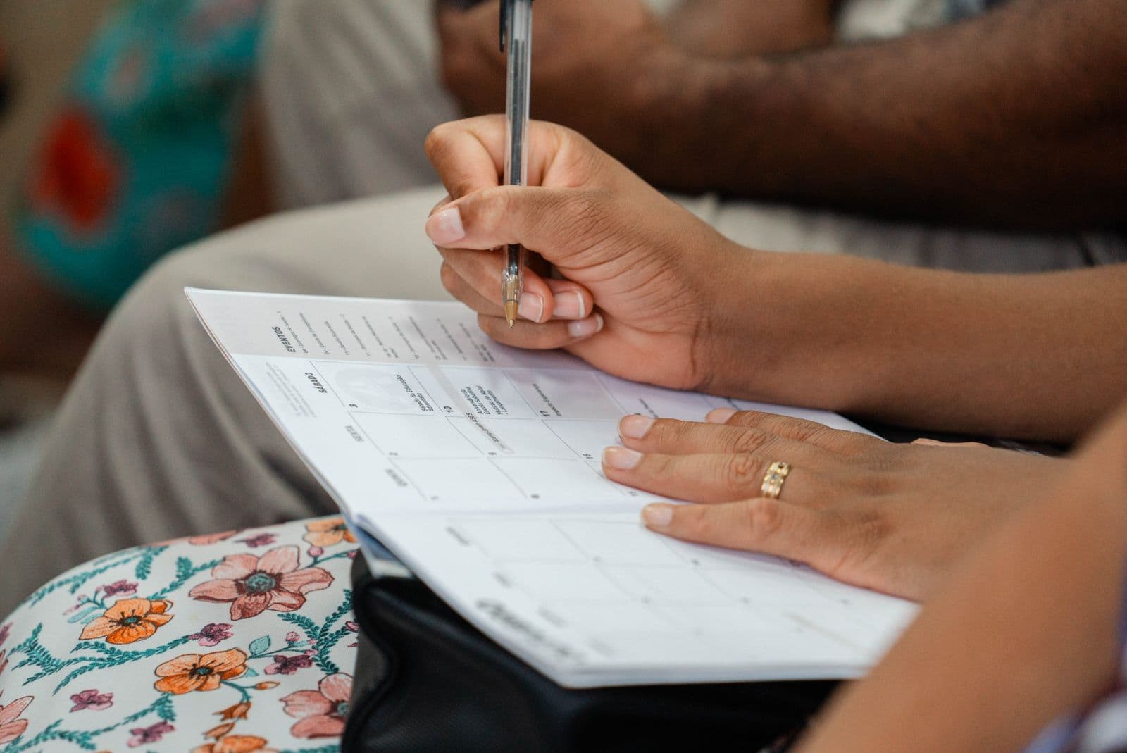 Close-up of a woman writing in a monthly calendar planner. Photo by Matheus Amaral on Pexels.