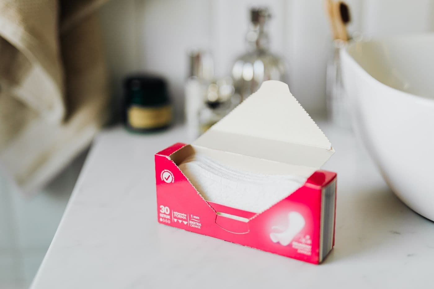 An open box of sanitary pads on a bathroom counter beside a sink. Photo by Karola G on Pexels.