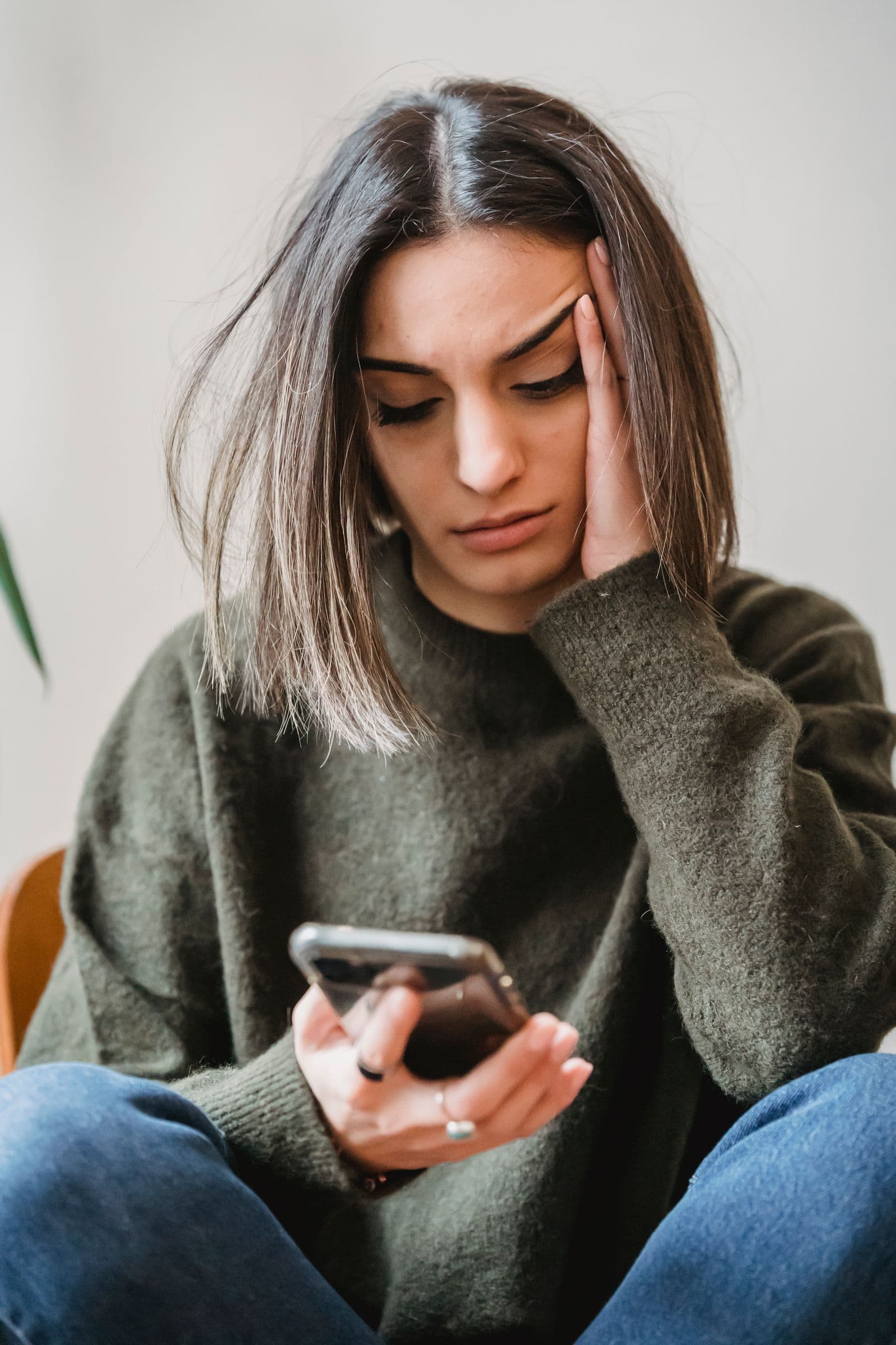 A young woman looking concerned while reading her phone. Photo by Liza Summer on Pexels.