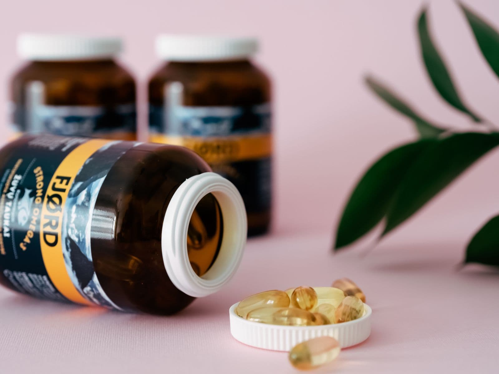Dietary supplement bottles and capsules on a pink surface. Photo by Natallia on Pexels.