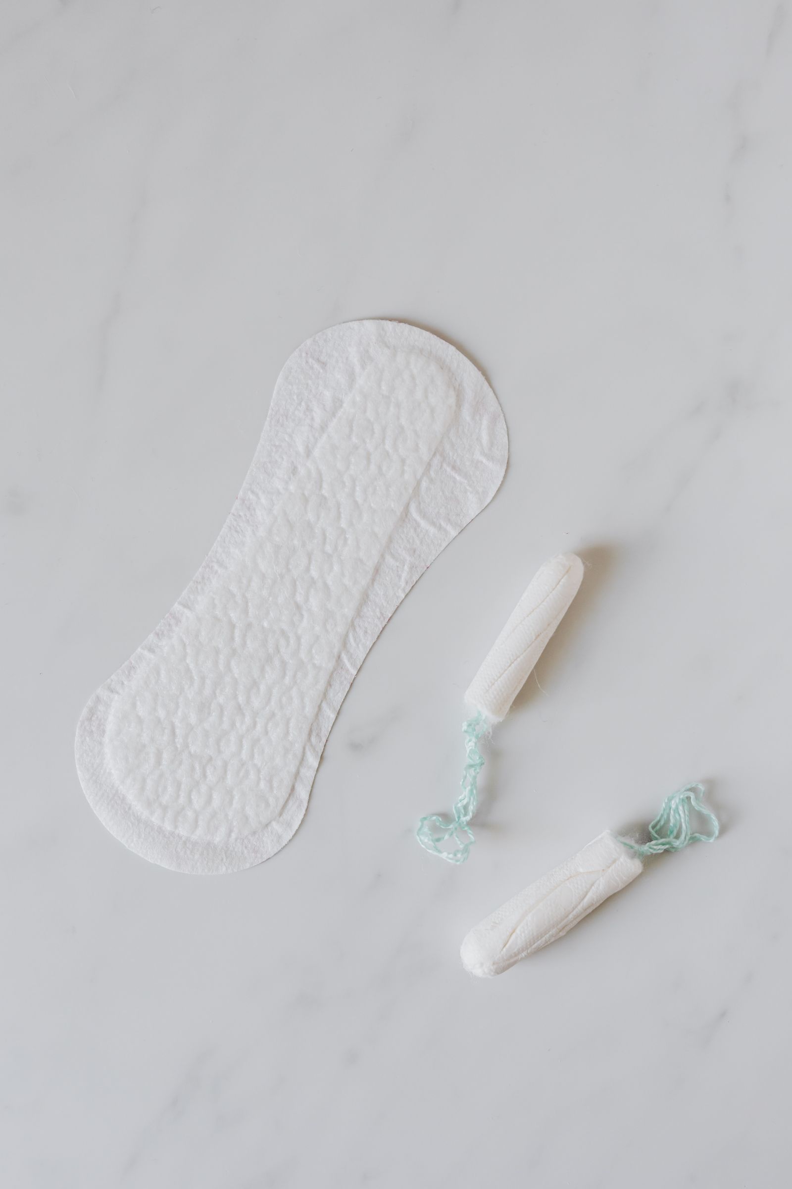 Tampons and a sanitary pad arranged on a marble surface